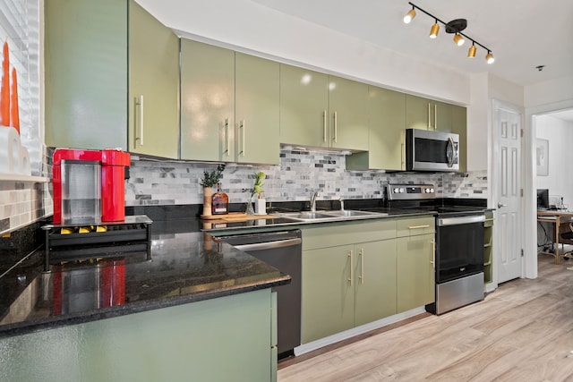 3901 Travis St Unit 121, Dallas, TX 75204 - kitchen with appliances with stainless steel finishes, green cabinetry, backsplash, light wood-style floors, and dark stone countertops
