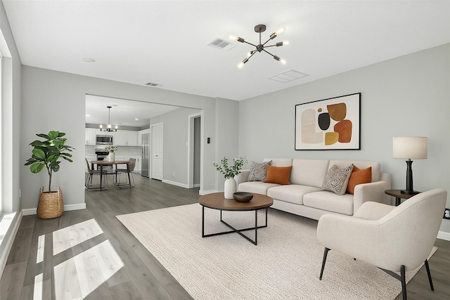living room with baseboards, wood finished floors, a notable chandelier, and visible vents