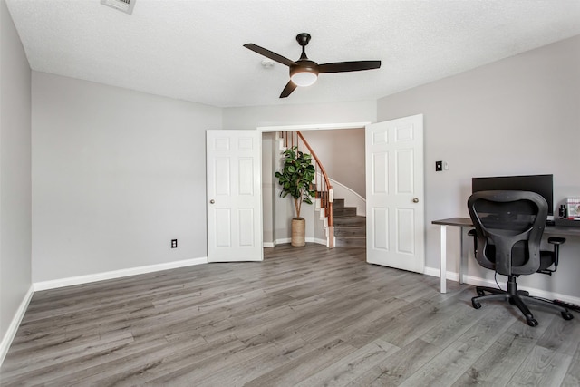 home office with visible vents, baseboards, ceiling fan, a textured ceiling, and wood finished floors