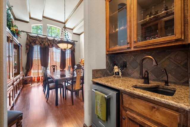 bar with lofted ceiling, a sink, tasteful backsplash, and crown molding
