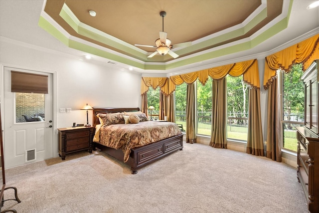 carpeted bedroom featuring a ceiling fan, visible vents, a raised ceiling, and crown molding