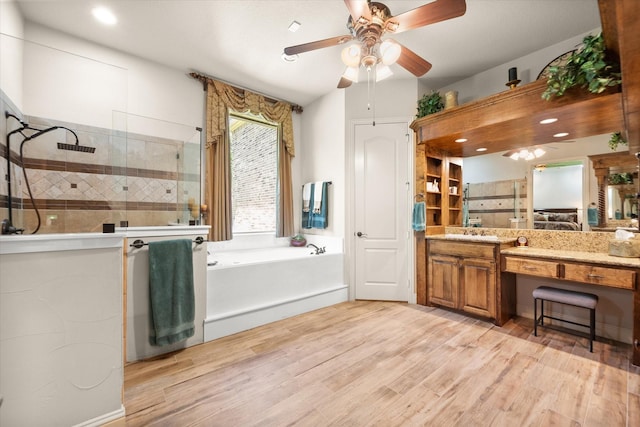 bathroom with a stall shower, wood finished floors, ceiling fan, a garden tub, and vanity