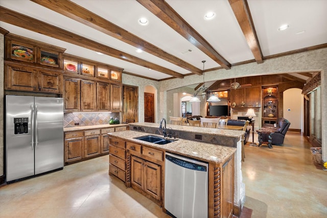 kitchen with open floor plan, a sink, arched walkways, and appliances with stainless steel finishes