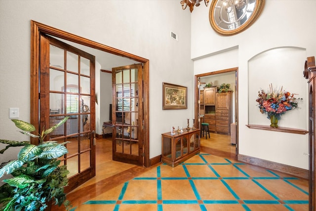 entrance foyer featuring arched walkways, visible vents, baseboards, and a high ceiling