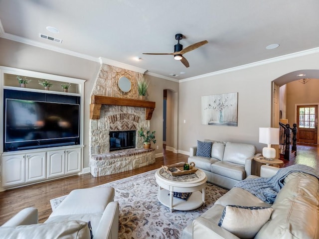 7212 Millard Pond Dr, Mckinney, TX 75071 - living room featuring ceiling fan, arched walkways, ornamental molding, a stone fireplace, and wood finished floors