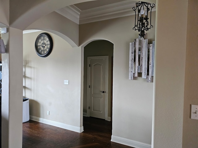 corridor with wood finished floors, baseboards, ornamental molding, and arched walkways
