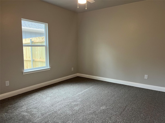 unfurnished room featuring dark colored carpet, a ceiling fan, and baseboards