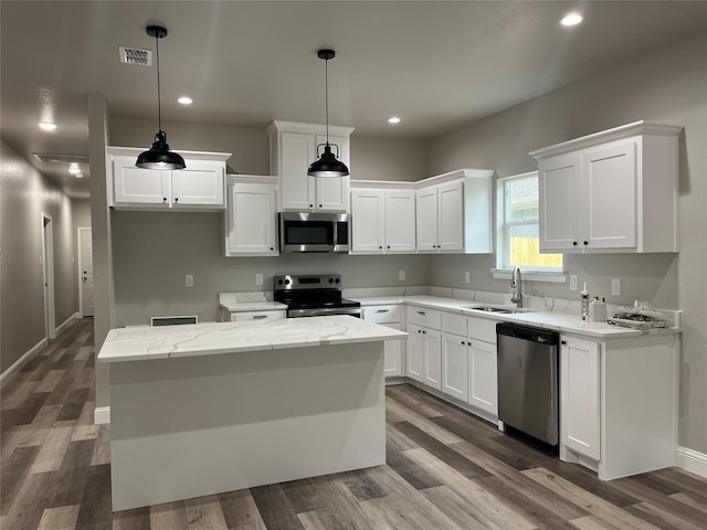 kitchen featuring a sink, appliances with stainless steel finishes, a center island, and dark wood-style flooring