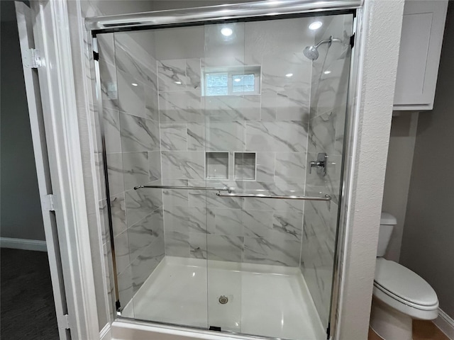 bathroom featuring toilet, baseboards, and a stall shower