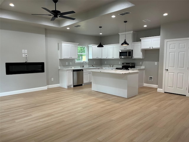 kitchen with white cabinets, appliances with stainless steel finishes, light countertops, baseboards, and light wood-type flooring