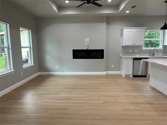 unfurnished living room with ceiling fan, visible vents, a sink, a raised ceiling, and light wood-style floors