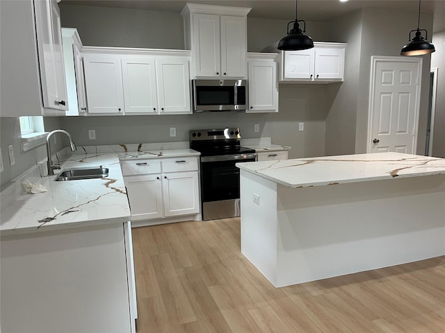 kitchen featuring a sink, light wood finished floors, appliances with stainless steel finishes, and white cabinets