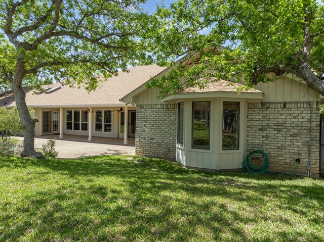 10019 Lost Oak Ridge Dr, Woodway, TX 76712 - rear view of property featuring brick siding, a lawn, a patio, a shingled roof, and board and batten siding
