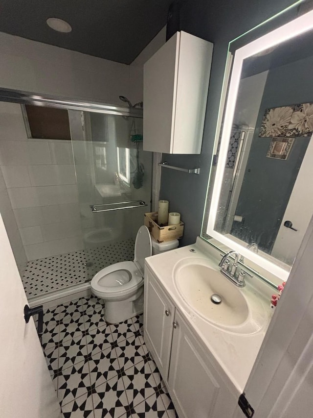 bathroom featuring toilet, vanity, and a stall shower