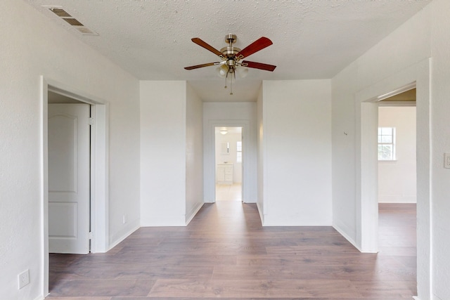2311 Market Ave, Fort Worth, TX 76164 - unfurnished room featuring visible vents, baseboards, ceiling fan, a textured ceiling, and wood finished floors