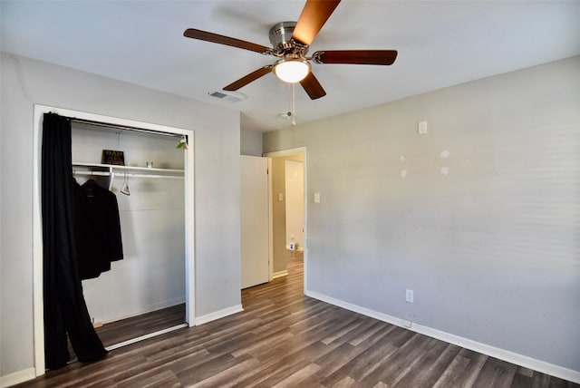 unfurnished bedroom with a closet, visible vents, baseboards, and dark wood finished floors