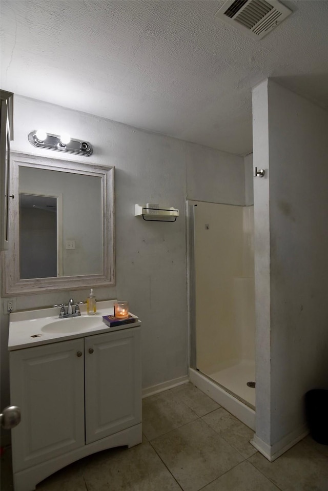 full bath featuring a shower stall, vanity, tile patterned flooring, visible vents, and baseboards