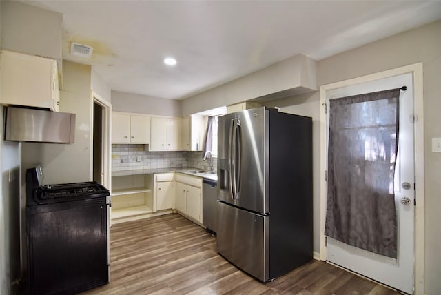 kitchen featuring tasteful backsplash, visible vents, light countertops, appliances with stainless steel finishes, and wood finished floors