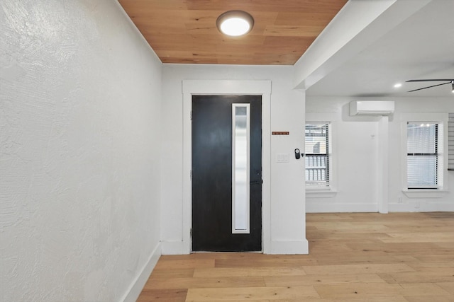 entrance foyer with light wood-style flooring, a wall mounted air conditioner, baseboards, a ceiling fan, and wooden ceiling