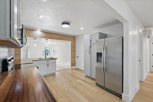 kitchen with stainless steel appliances, a sink, a peninsula, light wood-style floors, and recessed lighting
