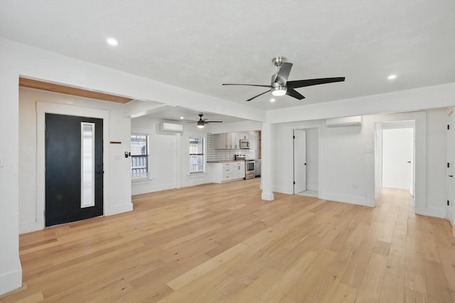 unfurnished living room featuring an AC wall unit, a ceiling fan, light wood-type flooring, recessed lighting, and baseboards