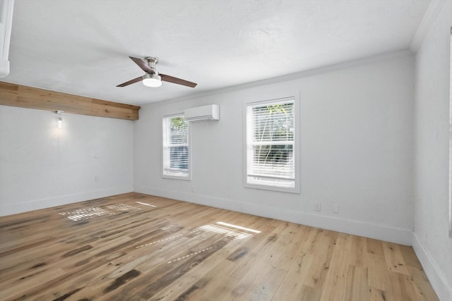 unfurnished room with a wall mounted air conditioner, wood finished floors, crown molding, baseboards, and a ceiling fan