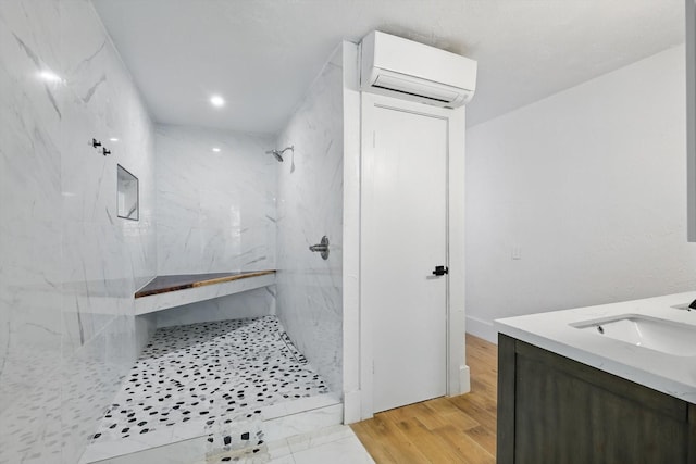 full bathroom with a wall mounted AC, a marble finish shower, vanity, and wood finished floors