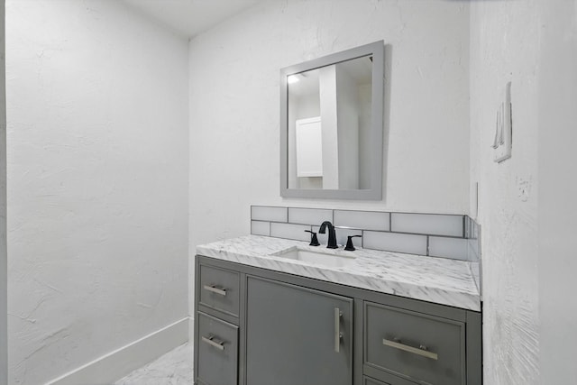 bathroom with marble finish flooring, vanity, and baseboards