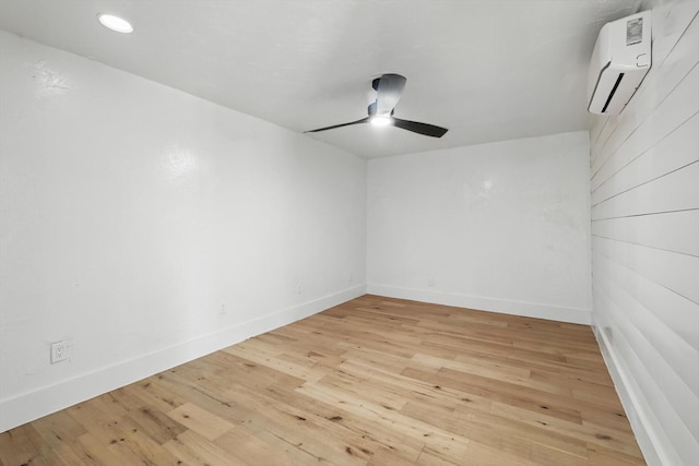 empty room featuring a wall mounted AC, ceiling fan, light wood-type flooring, and baseboards
