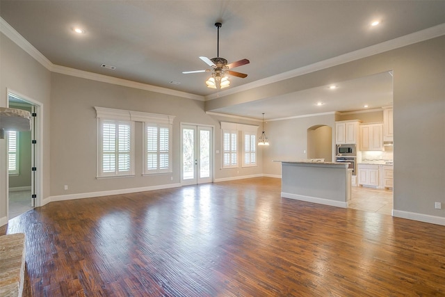 unfurnished living room with arched walkways, light wood-type flooring, a ceiling fan, and ornamental molding