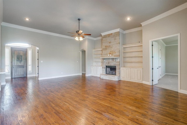 unfurnished living room featuring baseboards, arched walkways, a ceiling fan, crown molding, and wood finished floors