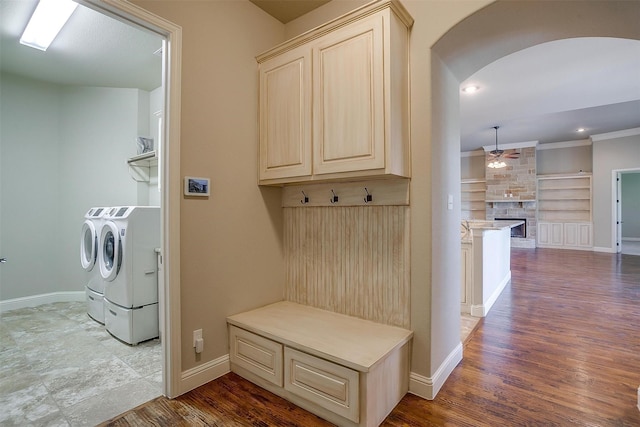 mudroom with a fireplace, arched walkways, a ceiling fan, wood finished floors, and washing machine and clothes dryer
