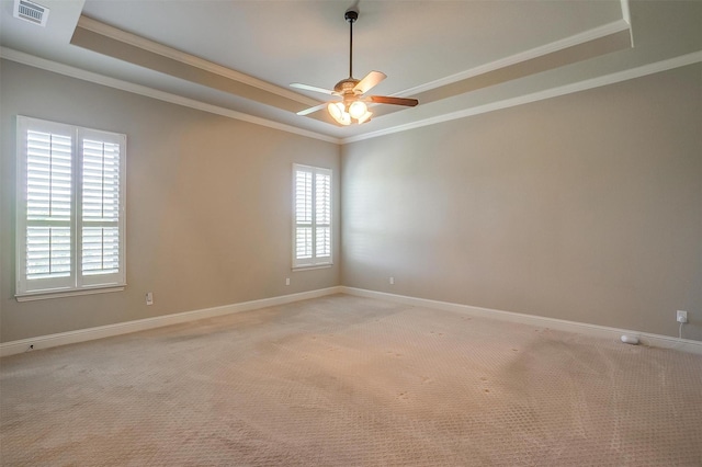 spare room with ceiling fan, visible vents, light colored carpet, and a raised ceiling