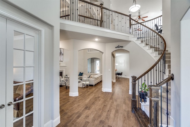 1765 Bramshaw Trl, Farmers Branch, TX 75234 - foyer entrance featuring wood finished floors, a towering ceiling, arched walkways, and stairs