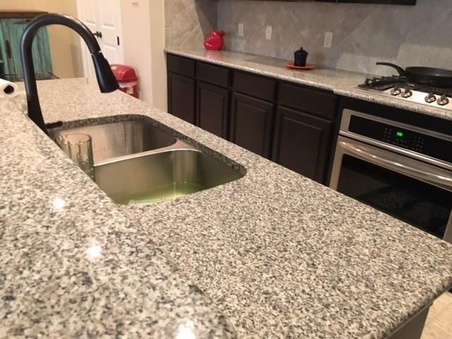 686 Pendle Forest Dr, Frisco, TX 75036 - kitchen with light stone countertops, a sink, backsplash, and appliances with stainless steel finishes