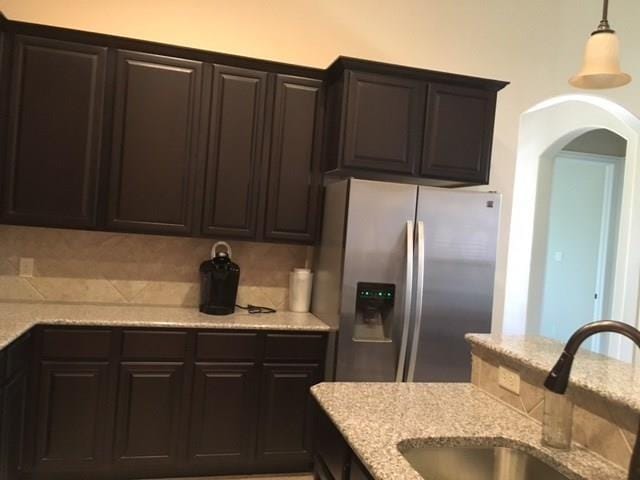 686 Pendle Forest Dr, Frisco, TX 75036 - kitchen featuring stainless steel fridge with ice dispenser, light stone countertops, arched walkways, pendant lighting, and a sink