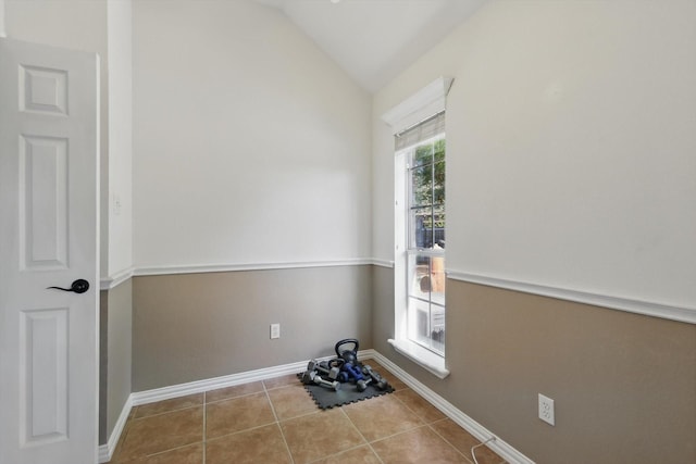 empty room featuring tile patterned floors, vaulted ceiling, and baseboards