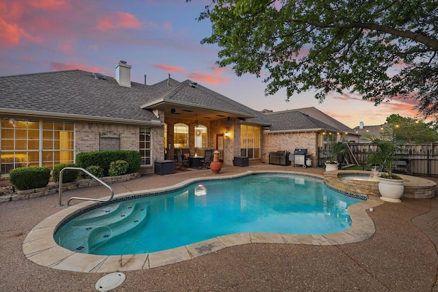pool at dusk with a patio area, grilling area, fence, an in ground hot tub, and a fenced in pool