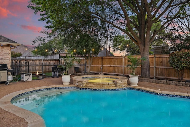 pool at dusk with a fenced backyard, a fenced in pool, and an in ground hot tub