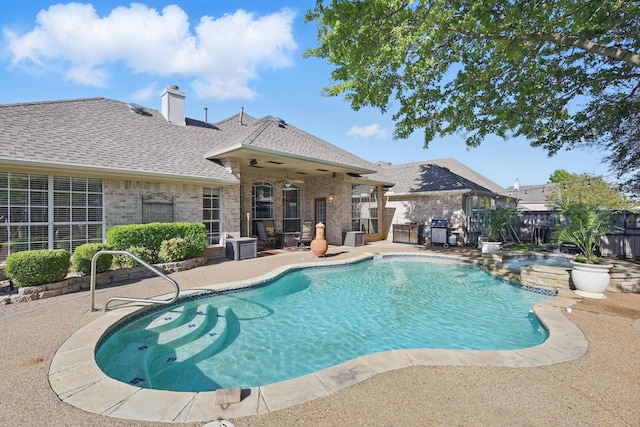 view of pool with fence, a patio area, a pool with connected hot tub, and a ceiling fan