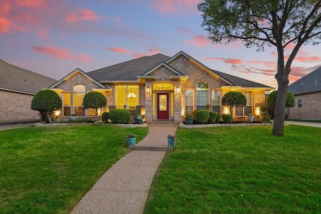 ranch-style house featuring a yard, stone siding, and brick siding