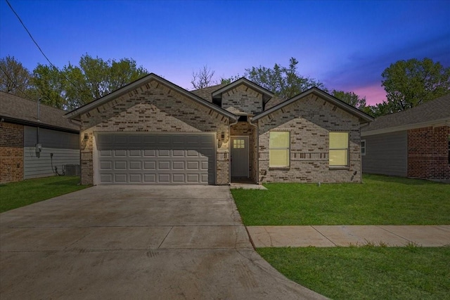 single story home featuring brick siding, a lawn, a garage, and driveway