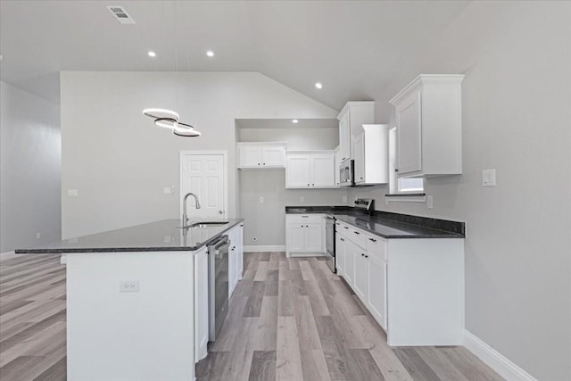 kitchen featuring visible vents, a sink, dark countertops, vaulted ceiling, and stainless steel appliances