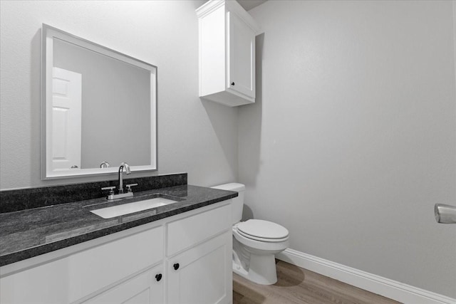 bathroom with vanity, baseboards, toilet, and wood finished floors