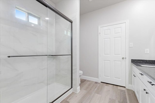 full bathroom featuring vanity, baseboards, a stall shower, toilet, and wood finished floors
