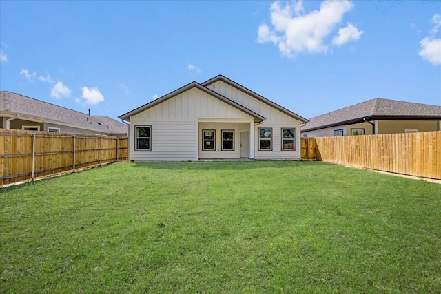 rear view of property with a yard, a fenced backyard, and board and batten siding