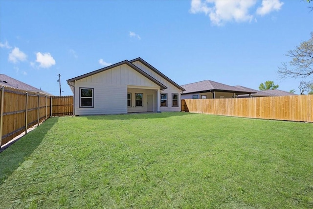 back of house with a yard and a fenced backyard