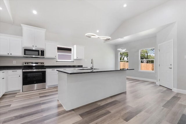 kitchen with white cabinets, dark countertops, lofted ceiling, and stainless steel appliances
