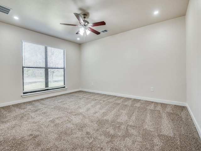 unfurnished room featuring carpet, visible vents, baseboards, and a ceiling fan