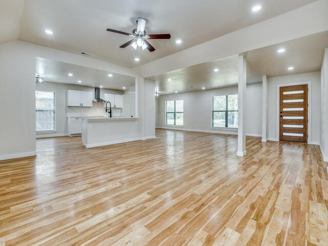 unfurnished living room featuring light wood-style floors, baseboards, visible vents, and ceiling fan